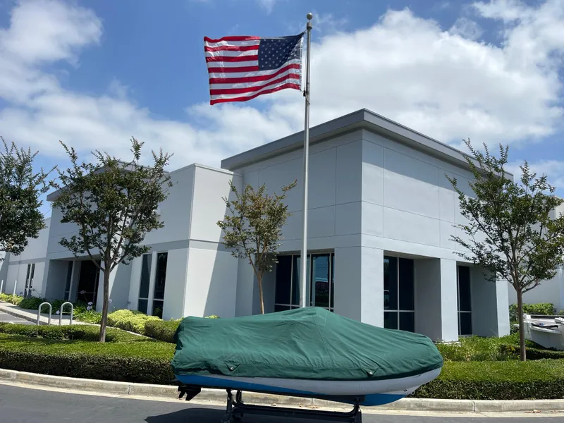 Slide: The Image of 2013 AB Inflatables Lammina 10 AL boat covered, near modern building and American flag. - 22