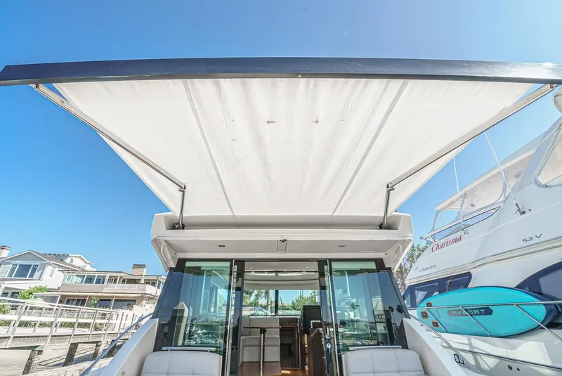 Slide: The Image of 2016 Tiara Yachts C44 Coupe with extended sunshade, docked under clear blue sky. - 17