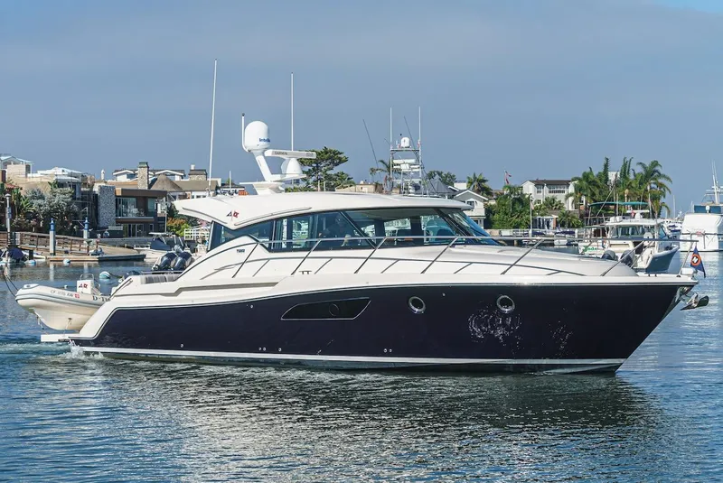 Slide: The Image of 2016 Tiara Yachts C44 Coupe cruising in a marina, showcasing sleek design and luxury features. - 2