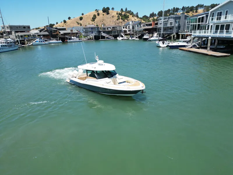 Slide: The Image of 2023 Chris-Craft Calypso 35 cruising in a scenic marina with waterfront homes. - 3