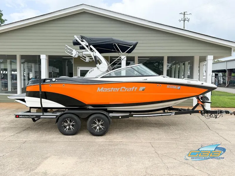 Slide: The Image of 2017 MasterCraft XT20 boat with orange and black design on a trailer. - 3