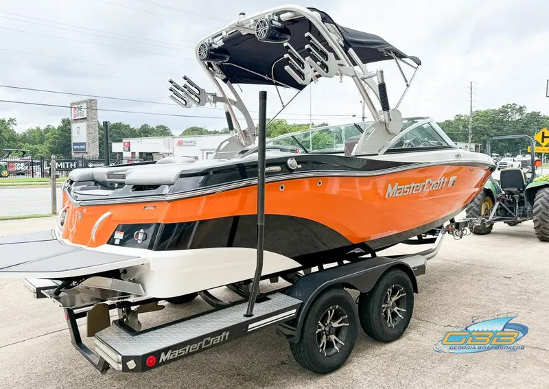 Slide: The Image of 2017 MasterCraft XT20 boat with orange and black design on a trailer. - 5