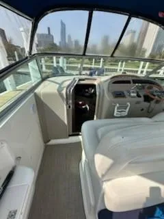 Slide: The Image of 2000 Sea Ray 310 Sundancer cockpit with helm, seating, and city skyline view. - 6