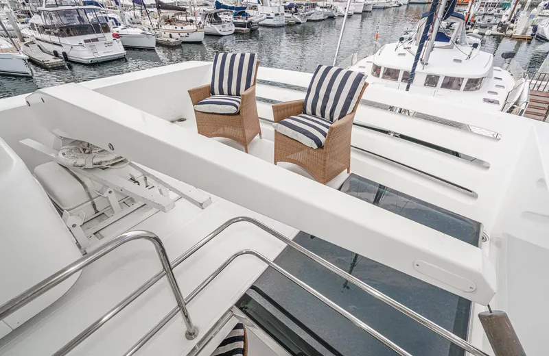 Slide: The Image of Deck view of 1999 Horizon 70 Motor Yacht with striped chairs in marina setting. - 19