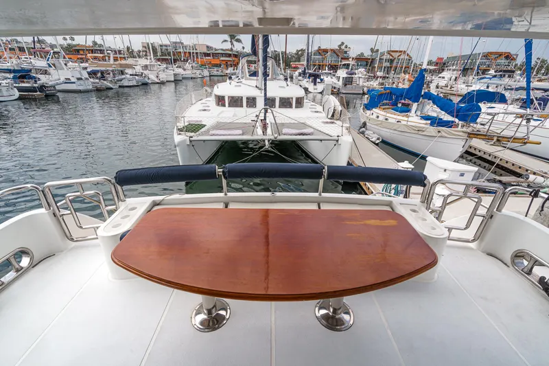 Slide: The Image of 1999 Horizon 70 Motor Yacht deck with wooden table, overlooking marina with various boats. - 26
