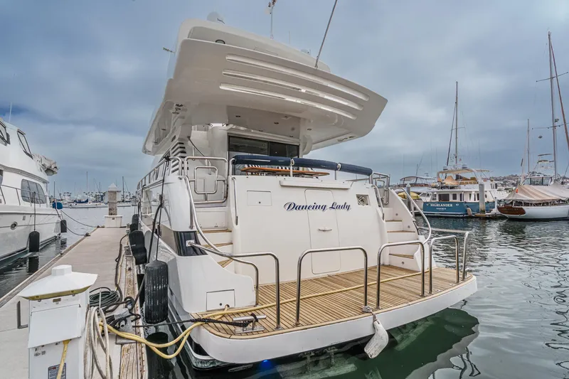 Slide: The Image of 1999 Horizon 70 Motor Yacht docked at marina, rear view with "Dancing Lady" name. - 7