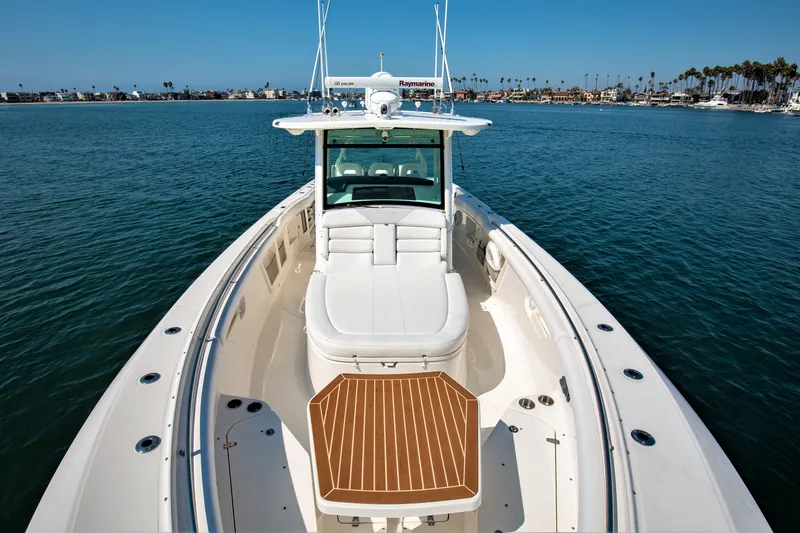 Slide: The Image of 2014 Boston Whaler 370 Outrage boat on calm water, showcasing spacious deck and seating. - 9