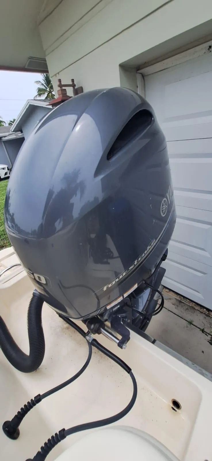 Slide: The Image of 2022 Scout 215 XSF boat with Yamaha outboard motor in a residential setting. - 23