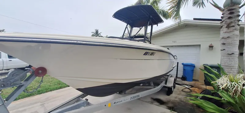 Slide: The Image of 2022 Scout 215 XSF boat on trailer, parked beside a house with palm trees. - 4