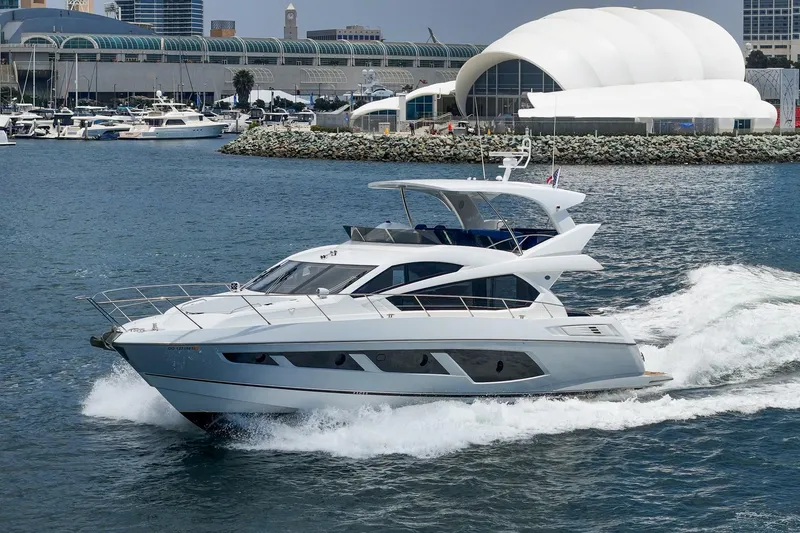 Slide: The Image of 2017 Sunseeker Manhattan 65 yacht cruising in a marina with modern architecture in the background. - 3