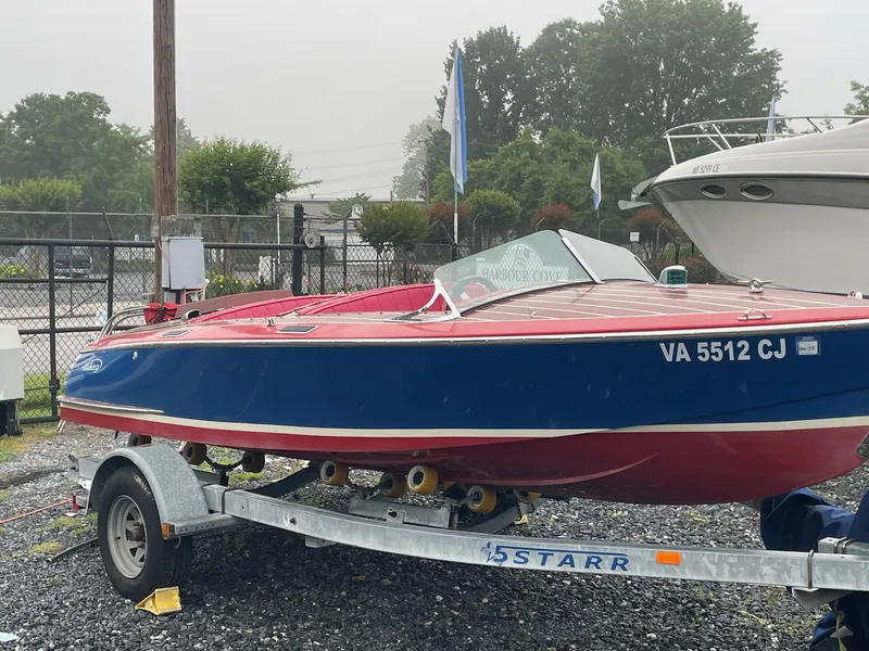 The Image of Red and blue Alsberg Brothers 17 boat on trailer, 2002 model, parked outdoors. - 0