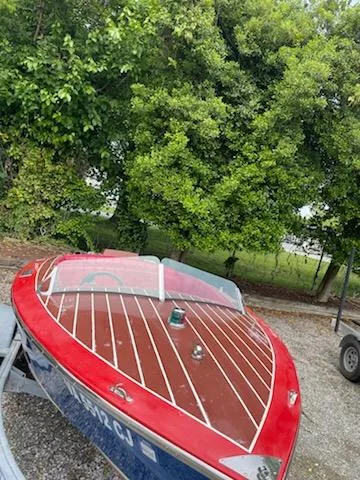 Slide: The Image of 2002 Alsberg Brothers 17 boat with red and wood finish, parked near lush green trees. - 13