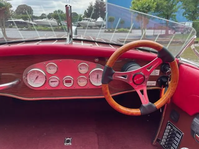 Slide: The Image of Interior of a 2002 Alsberg Brothers 17 boat with wooden steering wheel and red dashboard. - 9
