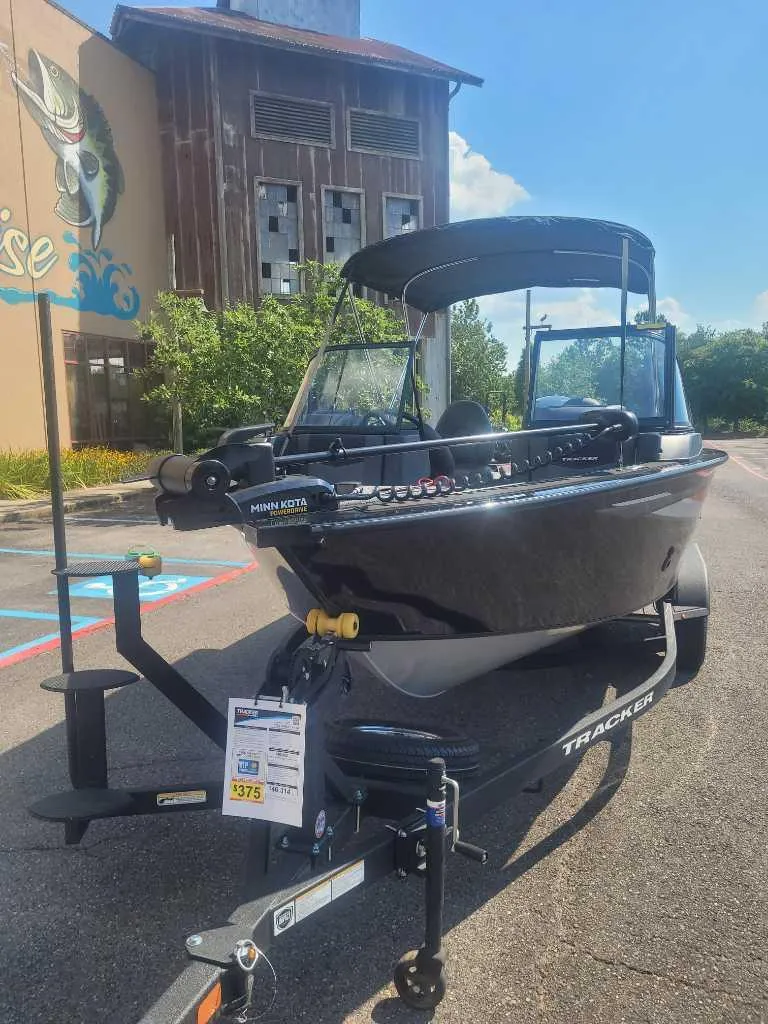 Slide: The Image of 2025 Tracker Targa V-18 WT boat on trailer, parked outdoors near rustic building. - 3