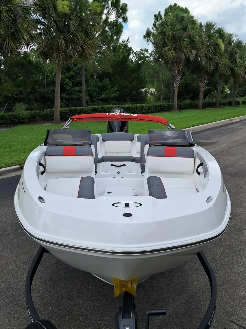 Slide: The Image of 2025 Tahoe T21 boat with red and gray seating, parked on a road with palm trees. - 3