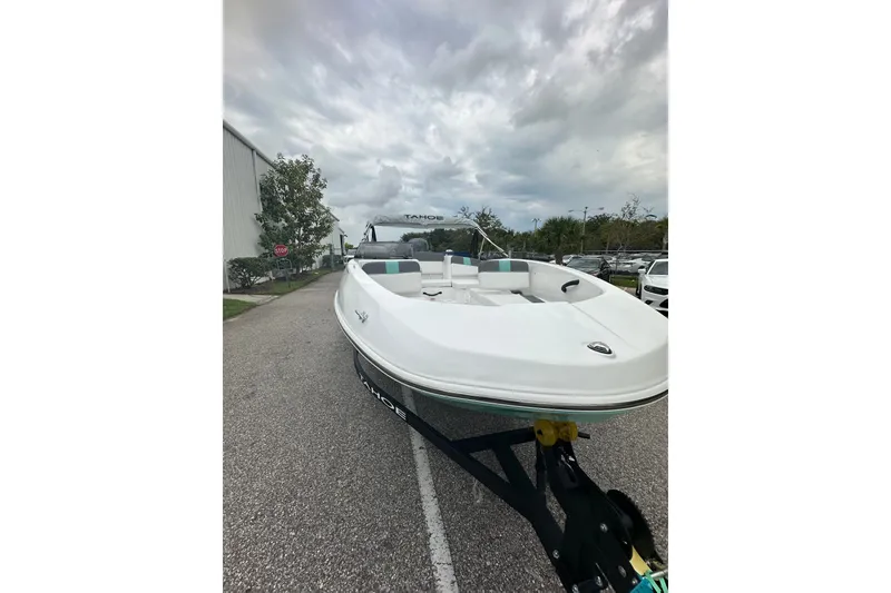 Slide: The Image of 2025 Tahoe T16 boat on trailer under cloudy sky, parked outdoors. - 2