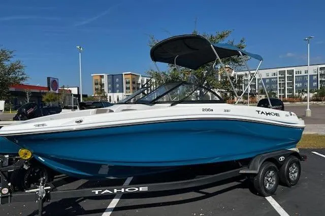 Slide: The Image of 2025 Tahoe 200 S boat with blue hull and canopy in parking lot. - 0