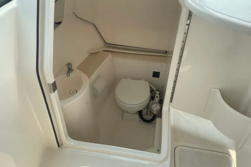 Slide: The Image of 2015 Pursuit DC 265 Dual Console boat interior bathroom with toilet and sink. - 18