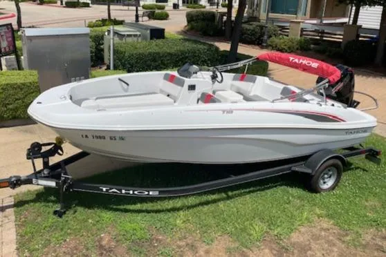 The Image of 2024 Tahoe T18 boat on trailer, white with red accents, parked outdoors. - 0