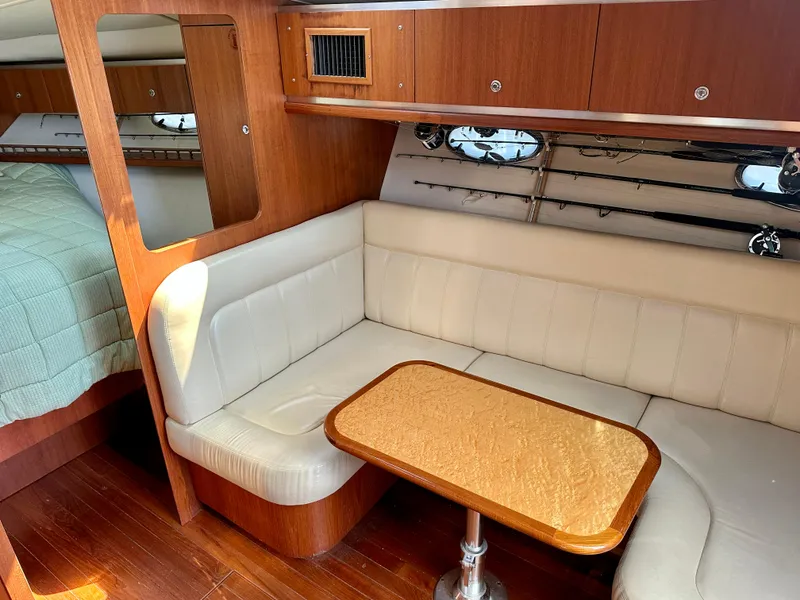 Slide: The Image of 2005 Tiara Yachts 3600 Open interior with beige seating, wooden table, and fishing rods. - 25