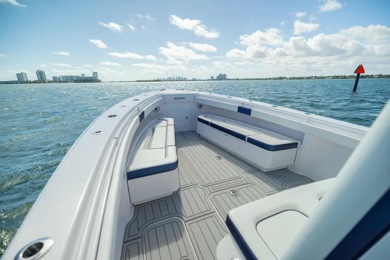 Slide: The Image of 2026 Reef Runner 340 boat on water, featuring spacious deck and seating, under clear skies. - 10