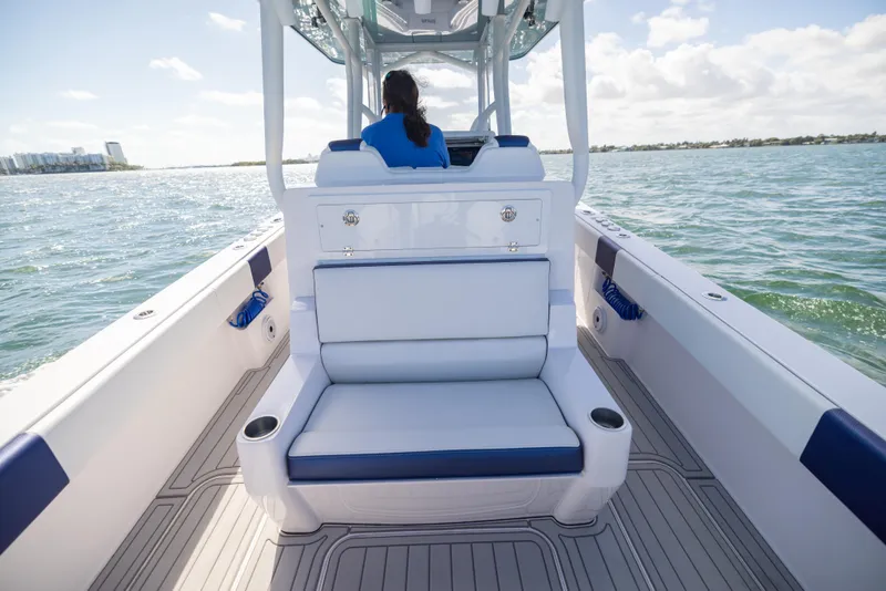 Slide: The Image of 2026 Reef Runner 340 boat interior with seating, navigating calm waters under a clear sky. - 13