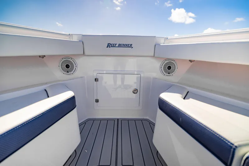 Slide: The Image of Interior of 2026 Reef Runner 340 boat with seating and speakers under a blue sky. - 16