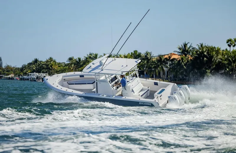Slide: The Image of 2026 Reef Runner 340 boat cruising on a sunny day near a tropical shoreline. - 4