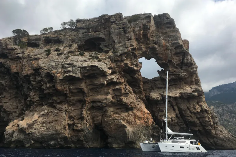 Slide: The Image of Sailing yacht Knysna 500SE 2026 near rocky cliff with natural arch formation. - 3