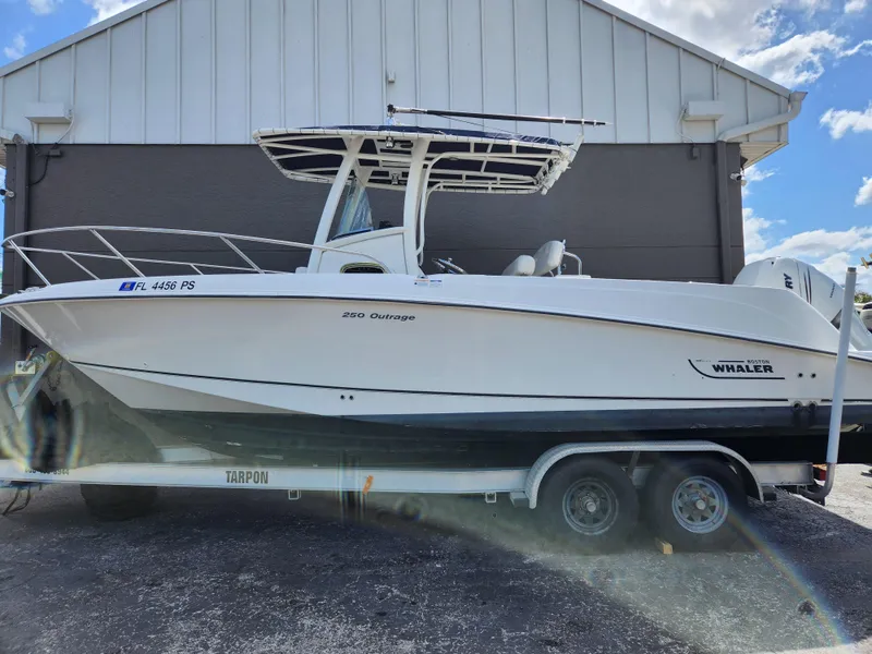 Slide: The Image of 2014 Boston Whaler 250 Outrage boat on trailer, parked outdoors. - 14