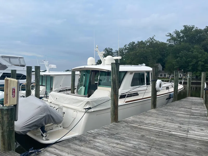 Slide: The Image of 2021 Sabre 48 Salon Express yacht docked at a marina with wooden piers. - 2