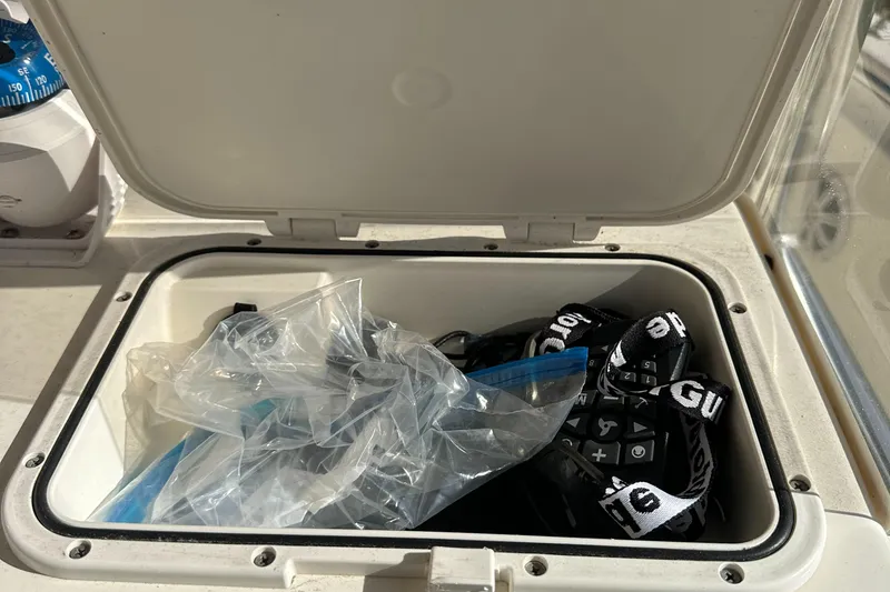 Slide: The Image of Open storage compartment on 2019 Bulls Bay 230 Center Console boat with various items inside. - 17