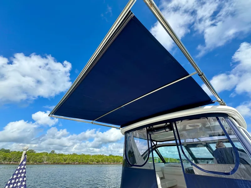 Slide: The Image of 2006 Tiara Yachts 3200 Open with blue canopy under clear sky. - 19