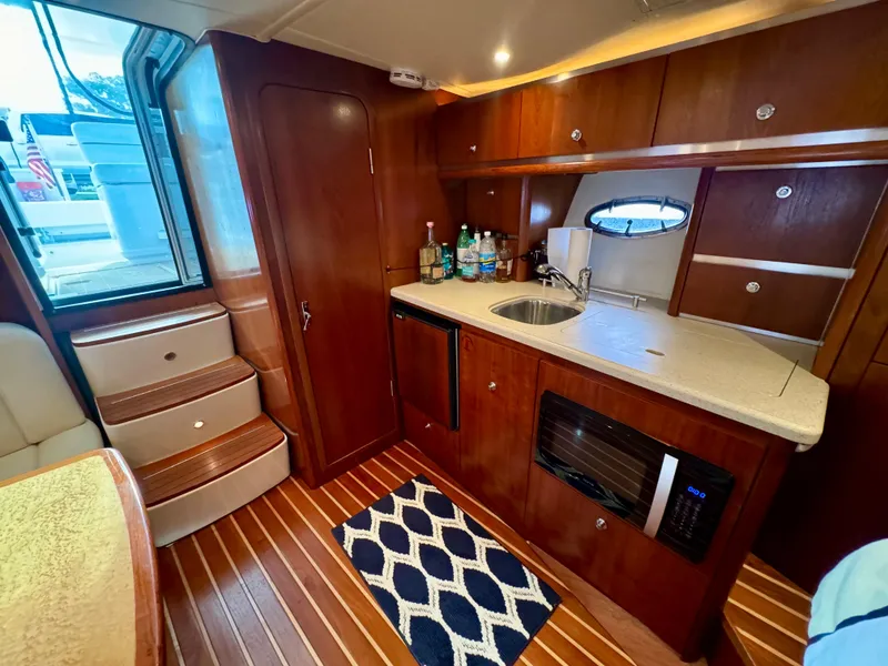 Slide: The Image of 2006 Tiara Yachts 3200 Open interior with kitchenette, wooden cabinetry, and modern amenities. - 36