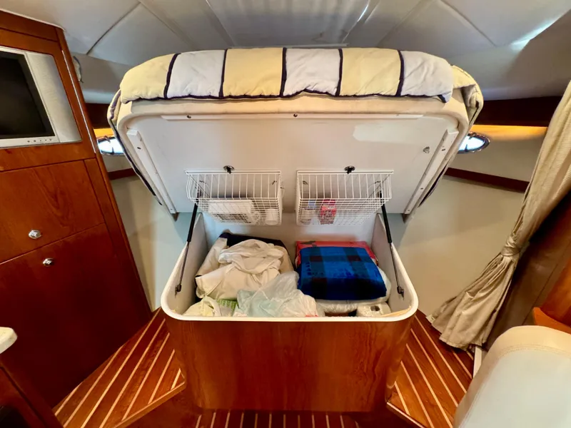 Slide: The Image of 2006 Tiara Yachts 3200 Open cabin with under-bed storage, wooden interior, and cozy bedding. - 41