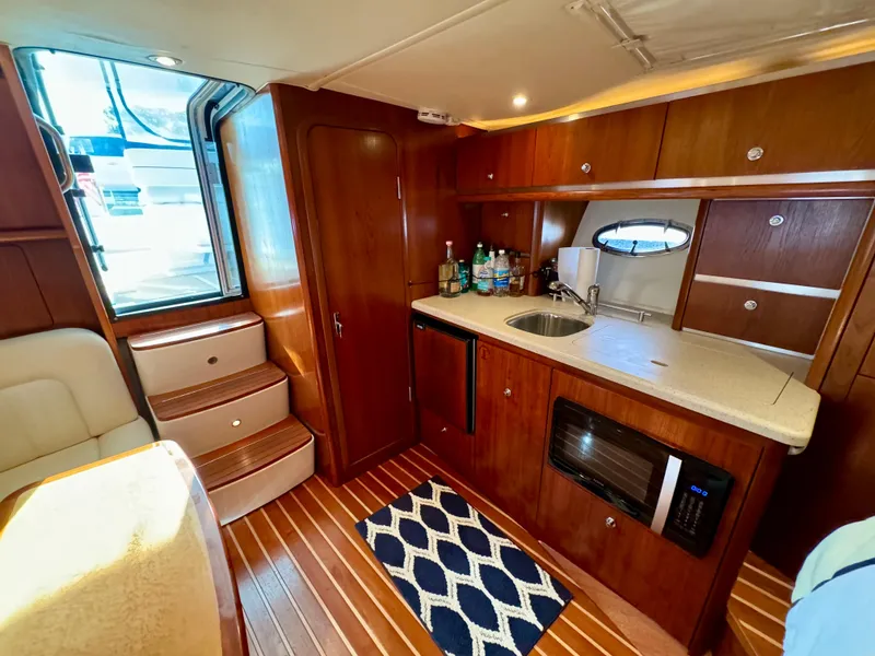 Slide: The Image of 2006 Tiara Yachts 3200 Open interior with kitchenette, wooden cabinetry, and modern appliances. - 44
