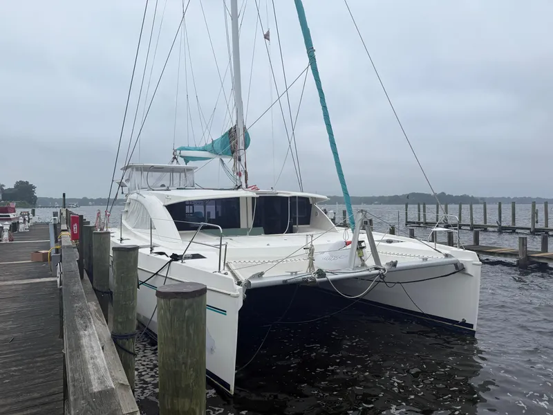 Slide: The Image of 2013 Leopard 48 catamaran docked, featuring a turquoise dinghy and overcast sky. - 1