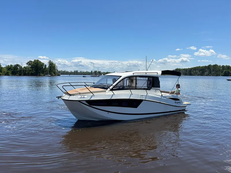 The Image of 2025 Bayliner TROPHY 25 EXPLORER boat cruising on a calm lake under a clear blue sky. - 0