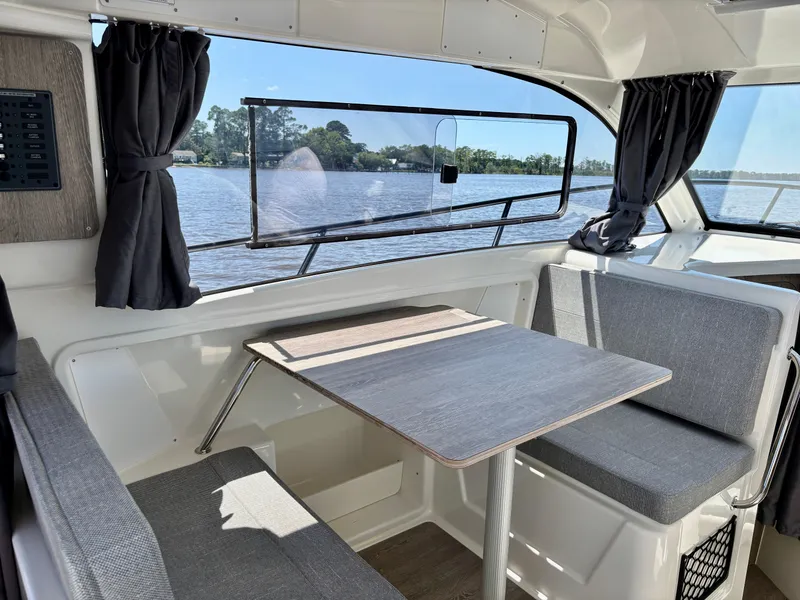 Slide: The Image of Interior of 2025 Bayliner TROPHY 25 EXPLORER with seating and table, overlooking water. - 4