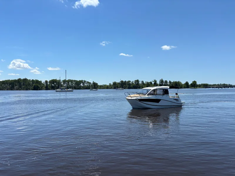 Slide: The Image of 2025 Bayliner TROPHY 25 EXPLORER boat on a calm lake under a clear blue sky. - 6