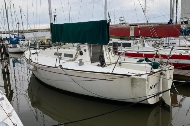 Slide: The Image of 1981 J Boats 30 sailboat docked in marina, featuring green sail cover. - 2