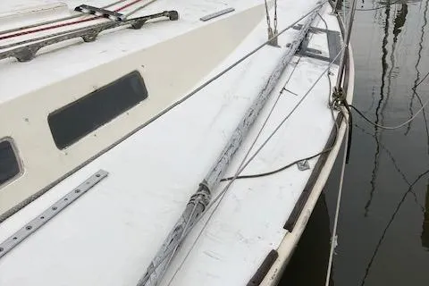 Slide: The Image of 1981 J Boats 30 sailboat deck with rigging and windows, docked in calm water. - 3