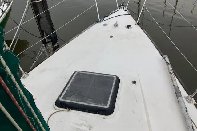 Slide: The Image of 1981 J Boats 30 sailboat deck with hatch, docked on calm water. - 4