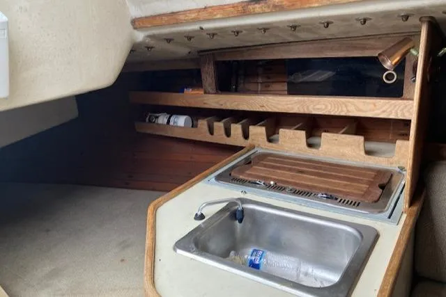 Slide: The Image of Interior of 1981 J Boats 30, featuring a compact sink and wooden storage shelves. - 9