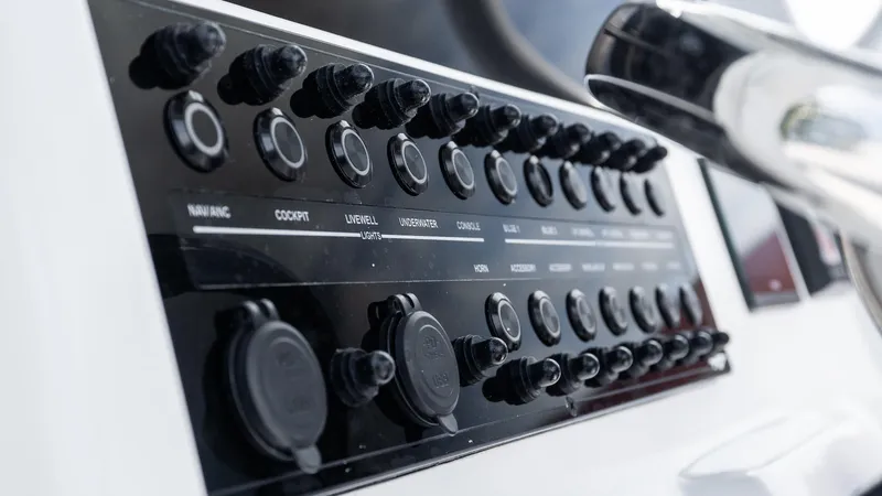 Slide: The Image of Control panel of 2026 Tidewater 256 CC Adventure boat with various switches and dials. - 16