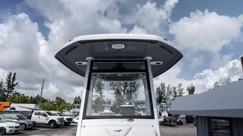 Slide: The Image of 2026 Tidewater 256 CC Adventure boat with T-top, parked outdoors under cloudy sky. - 24