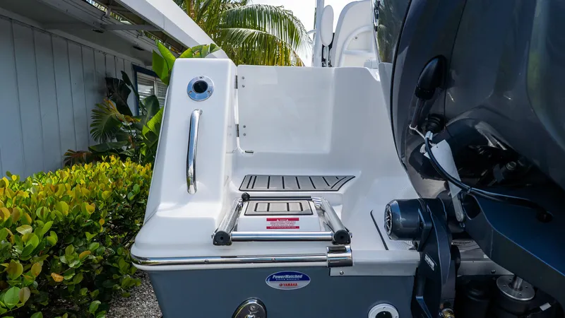 Slide: The Image of 2026 Tidewater 256 CC Adventure boat stern with ladder and motor, surrounded by greenery. - 6