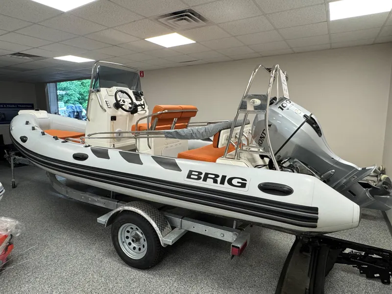 The Image of 2022 Brig Navigator 570 inflatable boat with Honda outboard motor on trailer indoors. - 13