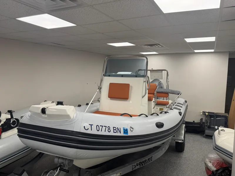 Slide: The Image of 2022 Brig Navigator 570 inflatable boat in showroom, featuring orange seating and white hull. - 14