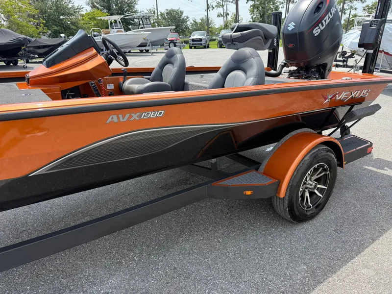 Slide: The Image of 2020 Vexus AVX 1980 boat with Suzuki engine, orange and black design, parked outdoors. - 4